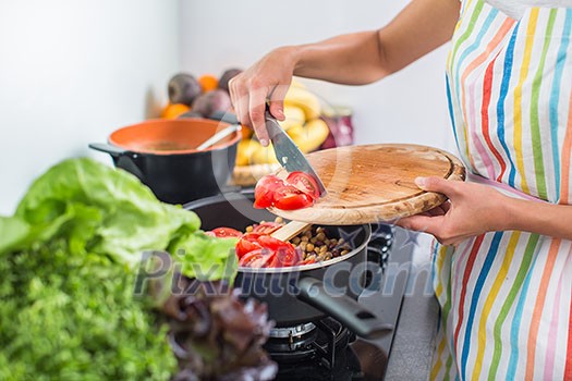 Young woman cooking in her modern kitchen (shallow DOF; color toned image)