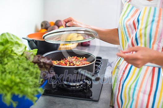 Young woman cooking in her modern kitchen (shallow DOF; color toned image)