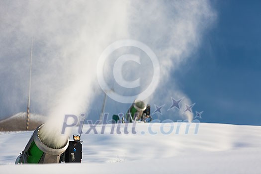 Snow-machine bursting artificial snow  over a skiing slope to alow for the skiing season to start