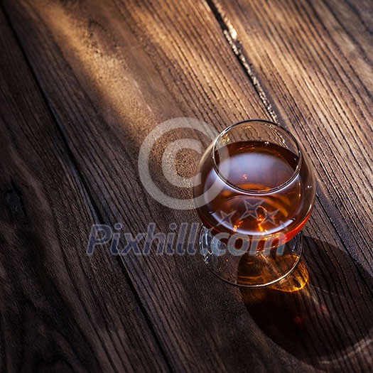 Cognac in glass on the wooden surface Cognac in glass on the wooden surface
