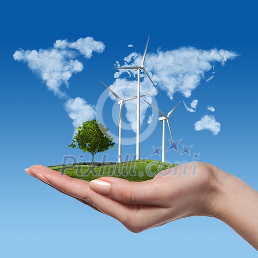 Wind turbines on meadow with tree holds in womans hand against blue sky and map of the world made of clouds. Worldwide Green energy concept Wind turbines on meadow with tree holds in womans hand against blue sky and map of the world made of clouds. Worldwide Green energy concept