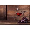 Red wine in glass with grape on wooden background