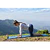 Sporty fit woman practices yoga asana bitilasana - cow pose outdoors in mountains