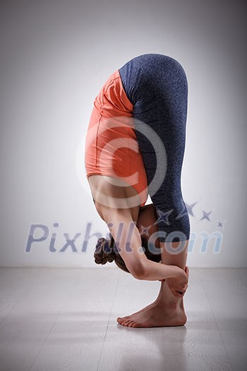 Beautiful sporty fit yogini woman practices yoga asana Uttanasana - standing forward bend pose Beautiful sporty fit yogini woman practices yoga asana Uttanasana - standing forward bend pose