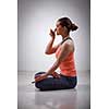 Beautiful sporty fit yogini woman practices pranayama breath control exercise in yoga asana Padmasana - lotus pose with Vishnu mudra in studio