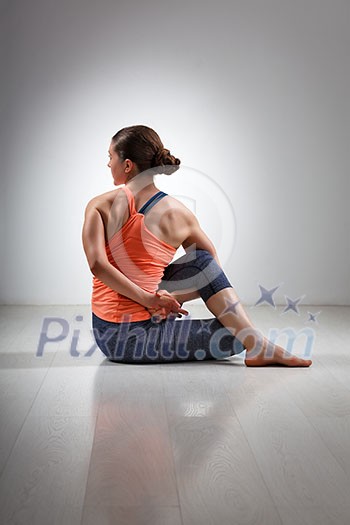 Beautiful sporty fit yogini woman practices yoga asana ardha matsyendrasana - half spinal twist pose Beautiful sporty fit yogini woman practices yoga asana ardha matsyendrasana - half spinal twist pose