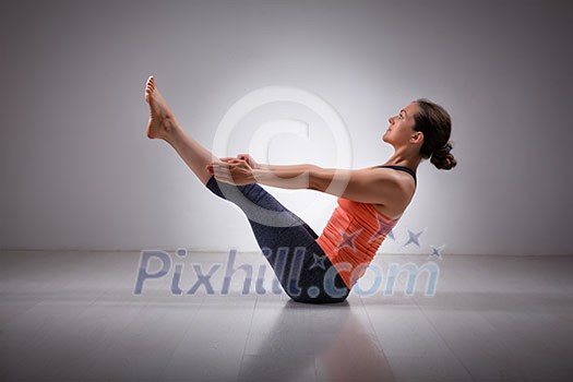 Beautiful sporty fit yogini woman practices yoga asana Paripurna navasana - boat pose Beautiful sporty fit yogini woman practices yoga asana Paripurna navasana - boat pose