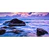 Tropical beach vacation background - panorama of waves and rocks on beach on sunset with beautiful cloudscape