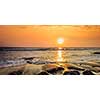 Tropical beach vacation background - panorama of waves and rocks on beach on sunset with beautiful cloudscape