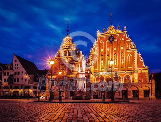Vintage retro effect filtered hipster style image of Riga Town Hall Square, House of the Blackheads and St. Roland Statue illuminated in the evening twilight, Riga, Latvia