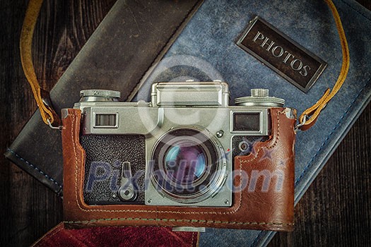 Photography concept background - old retro vintage camera on photo album on grunge wooden texture Photography concept background - old retro vintage camera on photo album on grunge wooden texture