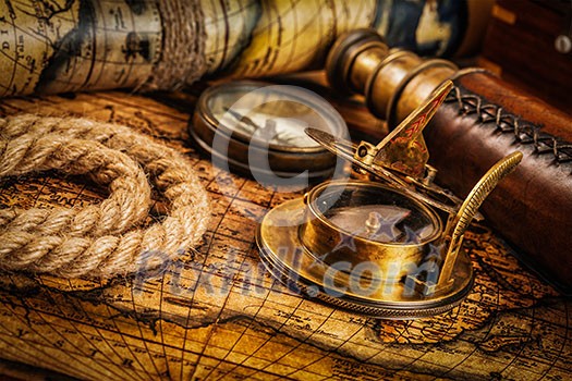 Travel geography navigation concept background - old vintage retro compass with sundial, spyglass and rope on ancient world map