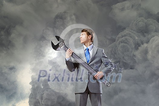 Young determined businessman with wrench in hands Young determined businessman with wrench in hands