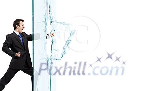 Young determined businessman breaking glass with karate punch