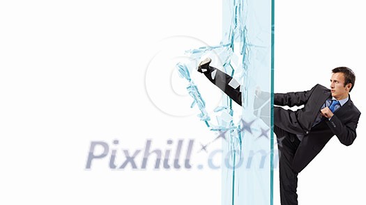 Young determined businessman breaking glass with karate kick Young determined businessman breaking glass with karate kick