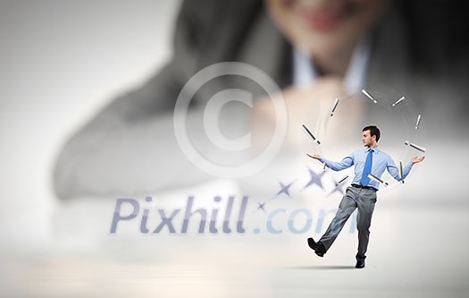 Businesswoman looking at miniature of man juggling with items Businesswoman looking at miniature of man juggling with items