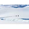 Group of people walking among snows of New Zealand Alps