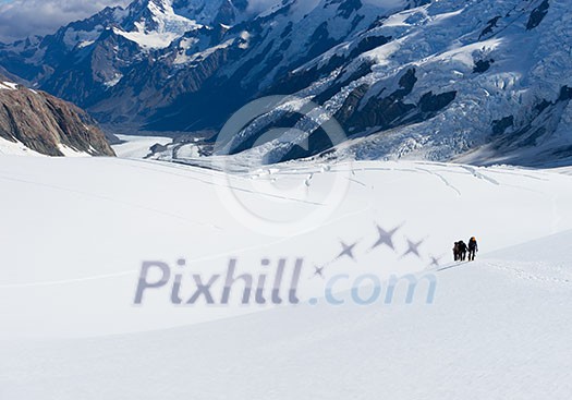 Group of people walking among snows of New Zealand Alps