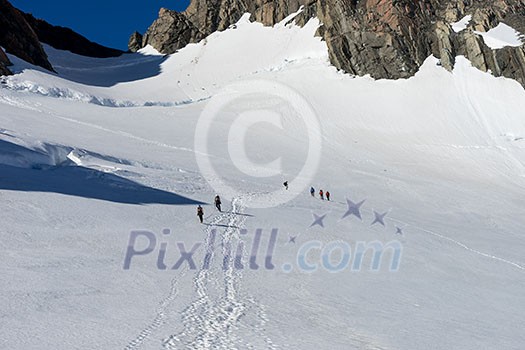 Group of people walking among snows of New Zealand mountains Group of people walking among snows of New Zealand mountains
