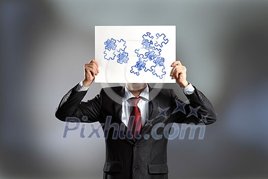 Businessman hiding his face behind paper sheet with sketches Businessman hiding his face behind paper sheet with sketches