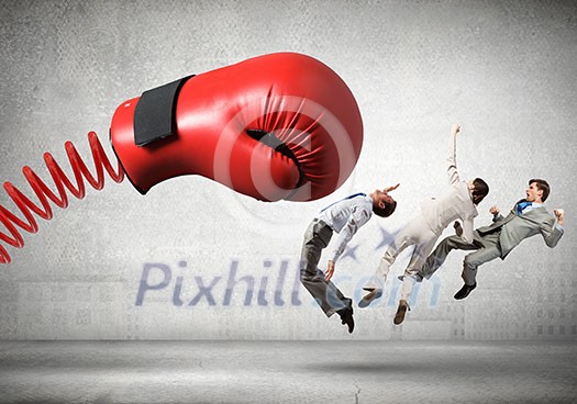 Boxing glove on spring striking group of businesspeople Boxing glove on spring striking group of businesspeople