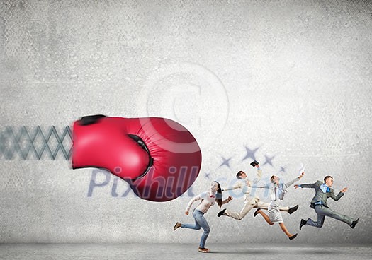 Boxing glove on spring striking group of businesspeople