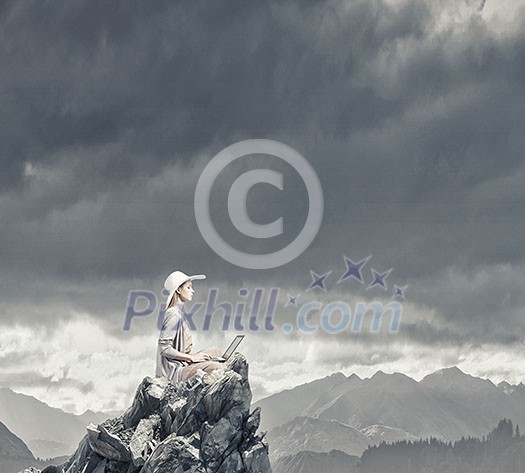 Woman in dress and hat sitting on top and working on laptop Woman in dress and hat sitting on top and working on laptop