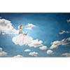 Woman in dress and hat sitting on cloud and working on laptop