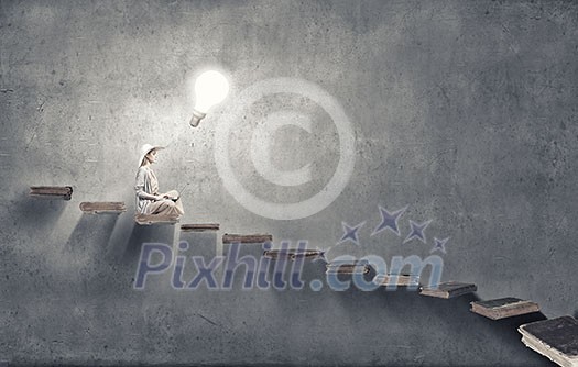 Woman in dress and hat sitting on books and working on laptop Woman in dress and hat sitting on books and working on laptop