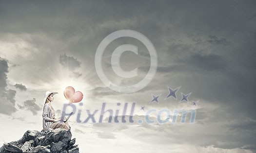 Woman in dress and hat sitting on top and working on laptop Woman in dress and hat sitting on top and working on laptop