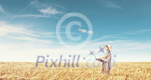Young lady in hat and long dress using laptop Young lady in hat and long dress using laptop