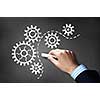 Businessman hand drawing with chalk gears mechanism as teamwork concept