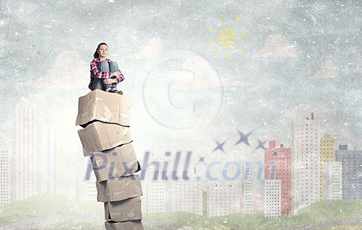 Smiling young woman sitting on stack of carton boxes Smiling young woman sitting on stack of carton boxes