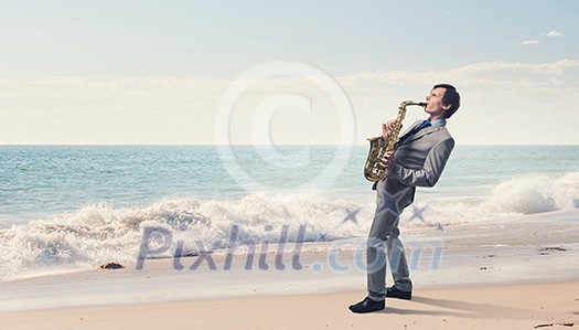 Young man playing saxophone on sea coast