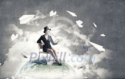 Pretty girl wearing retro hat siting on chair with tablet in hand. Elements of this image are furnished by NASA