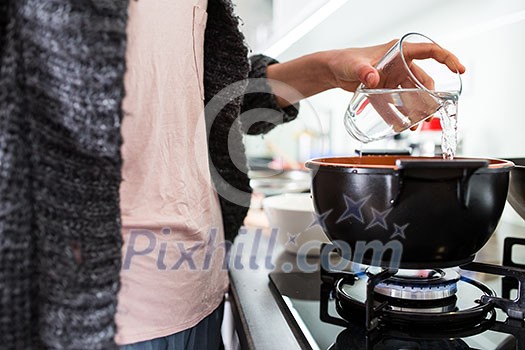 Young woman cooking in her modern kitchen (shallow DOF; color toned image)