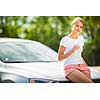 Young woman standing by her new car, having a refreshing drink of water before getting back on the highway during her long summer travel