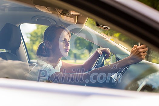 Young woman driving her car, on her way home from work - doing the daily commute