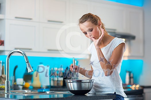 Pretty, young woman in her modern, clean and bright kitchen, fixing lunch/cooking/baking/making pancakes (color toned imagey; shallow DOF) Pretty, young woman in her modern, clean and bright kitchen, fixing lunch/cooking/baking/making pancakes (color toned imagey; shallow DOF)