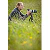 Pretty young woman with a DSLR camera outdoors, using a tripod, taking pictures