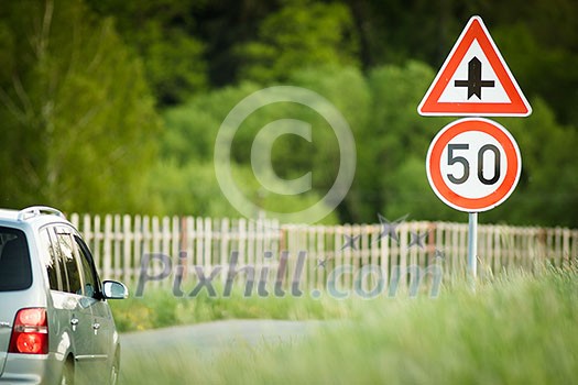 Car on a country road with limited speed and crossroad sign Car on a country road with limited speed and crossroad sign