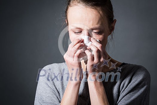 Young woman suffering from severe depression/anxiety/sadness, crying, tears coming from her eyes, blowing her nose