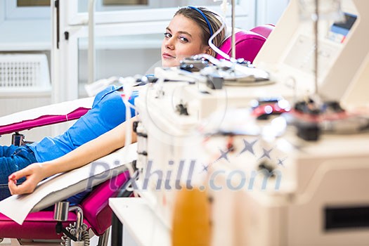 Pretty, young woman giving blood/plasma. Laying down while the procedure takes place (color toned image; shallow DOF) Pretty, young woman giving blood/plasma. Laying down while the procedure takes place (color toned image; shallow DOF)