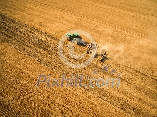 Aerial view of a tractor working a field after harvest Aerial view of a tractor working a field after harvest