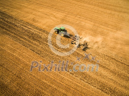 Aerial view of a tractor working a field after harvest