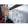 Pretty, young woman admiring splendid winter scenery from a cablecar cabin in high mountains (shallow DOF; color toned image)