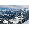 Splendid winter alpine scenery with high mountains and trees covered with snow, clouds hanging low in the valley