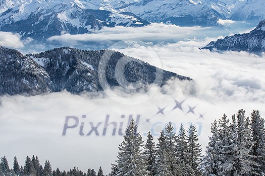 Splendid winter alpine scenery with high mountains and trees covered with snow, clouds hanging low in the valley Splendid winter alpine scenery with high mountains and trees covered with snow, clouds hanging low in the valley