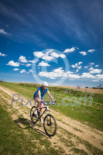 Pretty, young female biker outdoors on her mountain bike (motion blurred image)