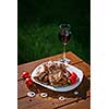 Grilled pork steaks on a wooden table with a glass of wine at sunset